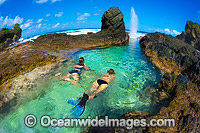 Snorkel divers exploring a tidal rock pool at Christmas Island, Indian Ocean, Australia.