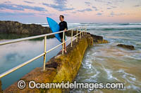Surfer exiting water at Sawtell Rock Pool. Sawtell, New South Wales, Australia.