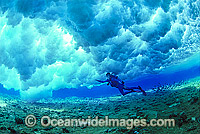 Scuba Diver beneath breaking wave over Coral reef. Great Barrier Reef, Queensland, Australia