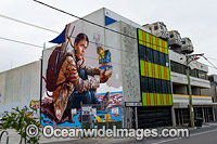 Giant graffiti plastered to the wall of four story building, End to End Building, situated in Collingwood, with three (real) metro train carriages perched on the roof. Melbourne, Victoria, Australia.