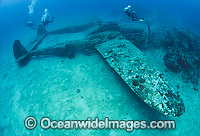 Scuba divers observing a Lockheed P-38 Lightning World War II American fighter aircraft, resting intact on the sea floor in Milne Bay, Papua New Guinea. Within the Coral Triangle.