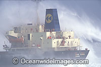 Huge wave breaking against a cargo ship during a storm. Cape Town, South Africa