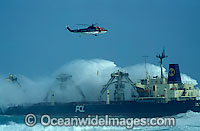 Rescue helicopter airlifting an operations worker from a ship engulfed by a huge breaking wave during a storm. Cape Town, South Africa