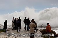 Spectators watch huge wave break on shore during a storm. Cape Town, South Africa