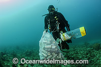 Scuba Diver with collected cans and garbage dumped on a coral reef offshore Palm Beach, Florida, USA. He is also removing an invasive introduced Volitans Lionfish (Pterois volitans), from the reef.