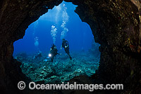 Scuba Divers explore the entrance to a lava tube off the Island of Lanai, Hawaii, Pacific Ocean.