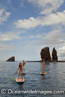 Three young people on stand-up paddle boards at Needles off the island of Lanai, Hawaii.