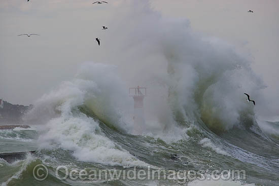 Wave breaking over lighthouse photo