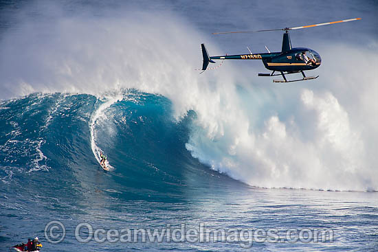 A helicopter filming a tow-in surfer at Peahi (Jaws) off Maui. Hawaii, Pacific Ocean. Photo - David Fleetham