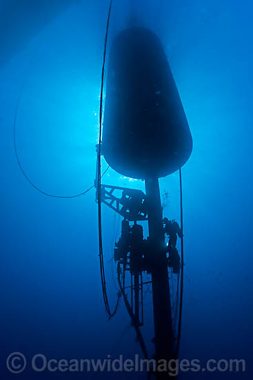 A Diver (MR) works on a massive wave energy buoy off Kaneoho Bay, Oahu. The 40-kW experimental buoy, employs the bobbing motion of the buoy to drive an electrical generator, that then sends power to the island via underwater cable, Hawaii. Photo - David Fleetham A Diver (MR) works on a massive wave energy buoy off Kaneoho Bay, Oahu. The 40-kW experimental buoy, employs the bobbing motion of the buoy to drive an electrical generator, that then sends power to the island via underwater cable, Hawaii. Photo - David Fleetham