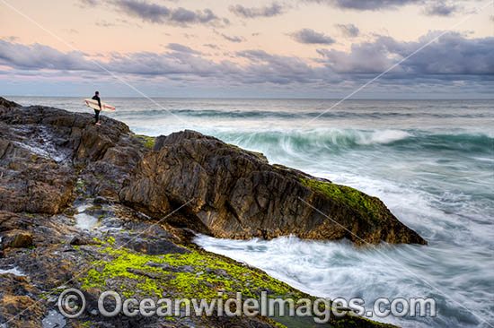 A Surfer with board under arm, prepares to enter the surf from a rocky coastal headland, situated at Sawtell, near Coffs Harbour, New South Wales, Australia. Photo - Gary Bell