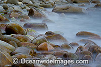 Wave breaking over smooth rocks, situated in Bluestone Bay, Freycinet National Park, Tasmania, Australia.