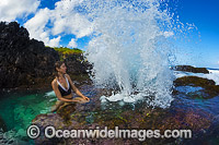 Swimmer exploring a blow-hole wave during low tide on the reef platform at Christmas Island, Indian Ocean, Australia.