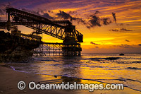 Sunset at Isabel Beach, with the phosphate loading wharf silhouetted in the foreground and Flying Fish Cove in distant background. Christmas Island, Indian Ocean, Australia.