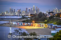 Brighton Beach at dusk with its famous bathing boxes, or boatsheds, with Melbourne city in the background. Victoria, Australia.